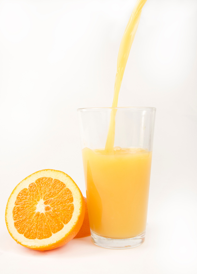 Pouring Orange Juice into Glass with Orange Halves